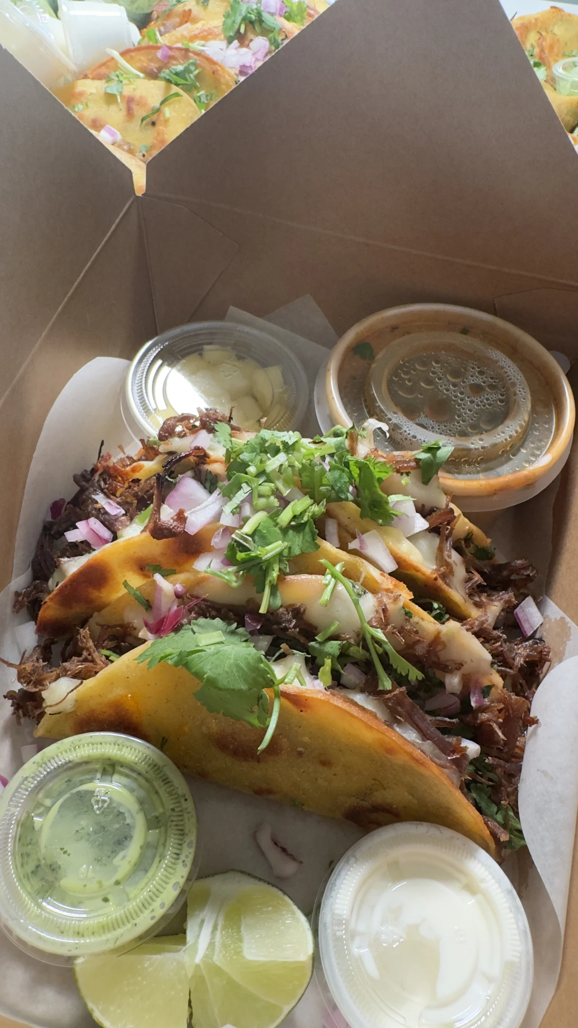 Tacos birria en boîte avec consommé, sauces et quartiers de lime